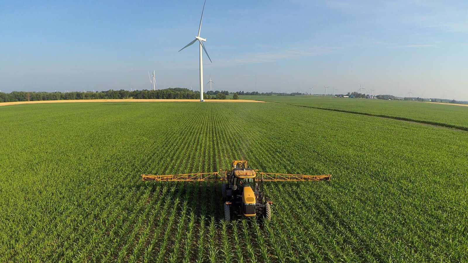 TCO Agromart Ltd. farm machinery harvesting fields with turbines in behind